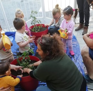 animatrice sensibilisant un groupe d'enfants par la création d'un potager et bacs de cultures