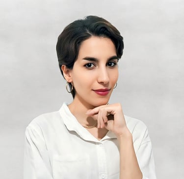 Portrait of a VISUALISE team member in a white shirt, gold necklace, and hoop earrings, against a neutral background.