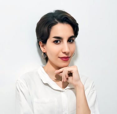 Portrait of a VISUALISE team member in a white shirt, gold necklace, and hoop earrings, against a plain white background.