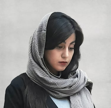 Portrait of a VISUALISE team member wearing a light-colored headscarf and dark outfit, with a plain, neutral background.