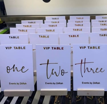 Assorted white Acrylic Table Numbers with black and gold script, labeled from 'one' to 'four'