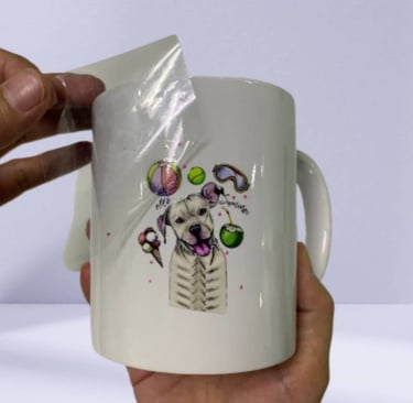 UV DTF sticker being applied to a white ceramic mug with a dog design.