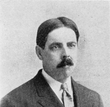 um homem de terno e gravata com bigode