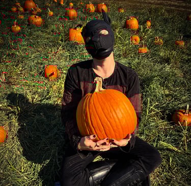 Man poses in a pumpkin patch wearing a pup mask.
