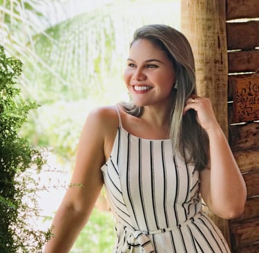 Priscila, Pri Cílios extensionista de cílios, sorrindo em fazenda com vestido branco.