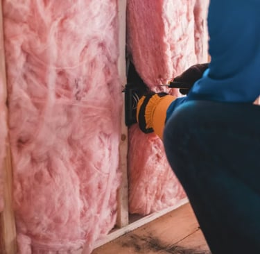 a man in a blue jacket and gloves is using a hammer to install a insulation