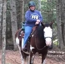 a woman riding a horse in the woods