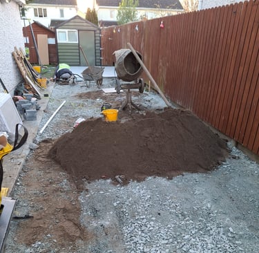 a pile of dirt in a backyard with a concrete wall