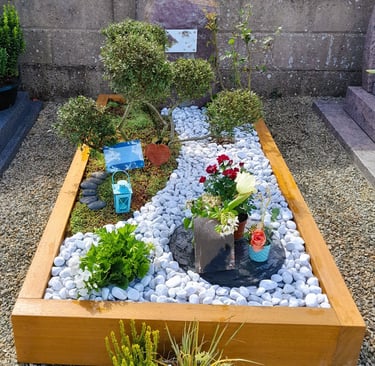 Jardin du souvenir avec cadre bois, décor de galets blancs sinueux et artopierre