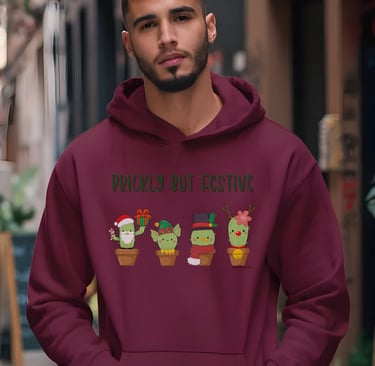 Man wearing maroon hoodie with “Prickly but Festive” cactus design — Christmas hoodie for plant lovers by Miss Chatty Plants