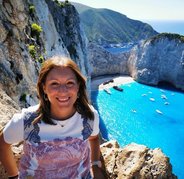 a woman standing on a cliff overlooking a cliff and beach
