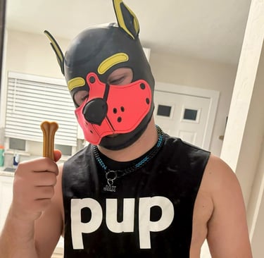 Man in pup mask and t-shirt holding a doggie rawhide chew.