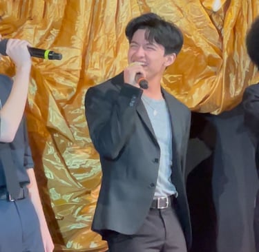 young male singer smiling and  singing into microphone