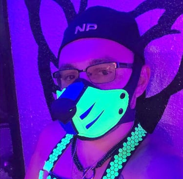 A man. posing in a pup snout mask in a black light.