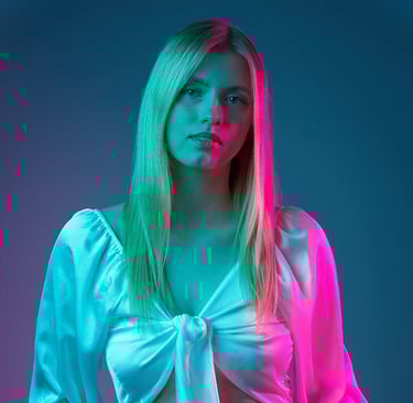 Portrait einer Frau mit weißer Bluse und Jeans vor farbig beleuchtetem Hintergrund