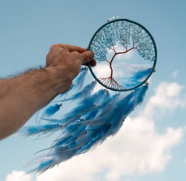 a person holding a blue feathered dream catcher