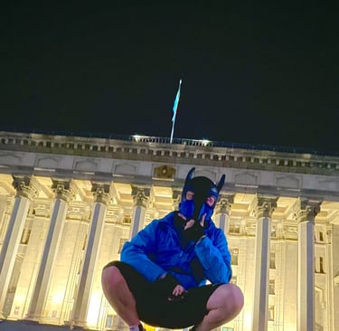 Man in pup mask posing near monument at night.