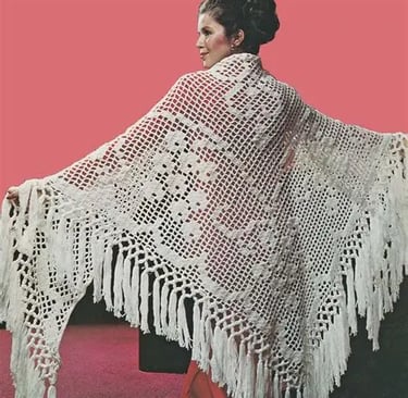 a woman in a white crochet shawl with fringes and red dress