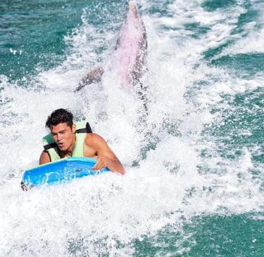 a man riding a surfboard in the ocean dolphines punta cana