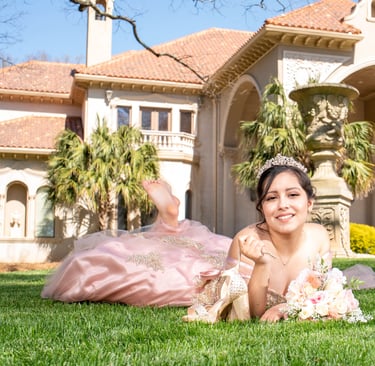 quinceanera princess in a pink dress laying on the grass