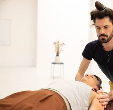 practitioner touching arms of client focused intently on client laying on a massage table