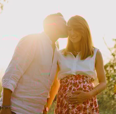 una donna incinta e un uomo che si baciano al tramonto
