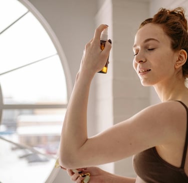 a woman in a brown tank top spraying face mist on her face