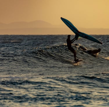 Wingfoil surfing on a wave during sunset