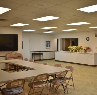 a fellowship hall with kitchen and tables with chairs