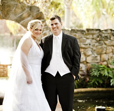 a bride and groom standing in front of a fountain