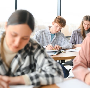 Diverse high school students studying and taking notes in a bright modern classroom.