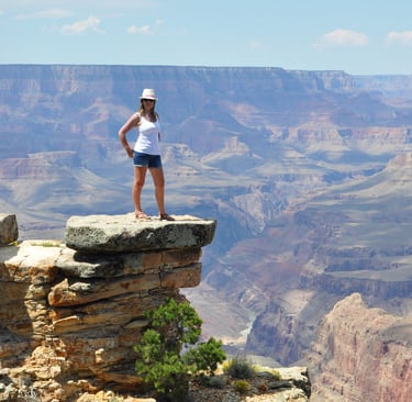 a woman standing on a cliff overlooking the grand canyon
