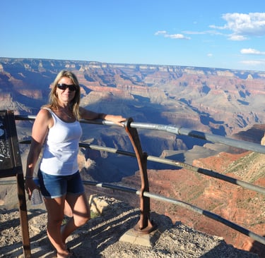 a woman standing on a railing with the grand canyon in the background