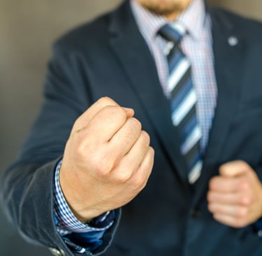 A man in a suit clinching his fists.