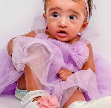 a baby girl in a purple dress and white shoes