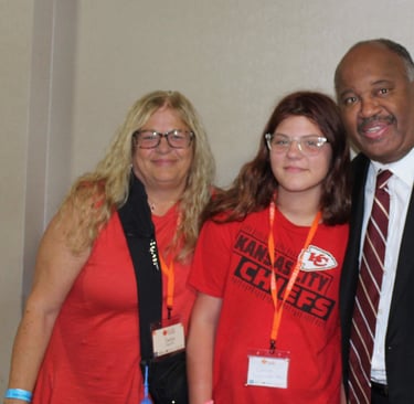 Dominic Carter at the Missouri Kinship Conference speaking with a teenager and her aunt who is raising her — highlighting fam
