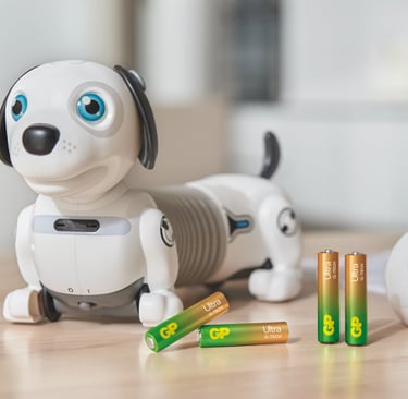 A toy robot dog on a wooden table, with GP Ultra AAA batteries in front
