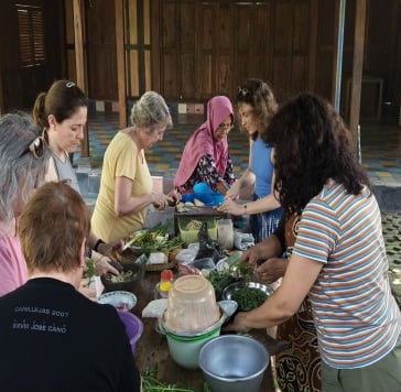a group of people standing around a table with food