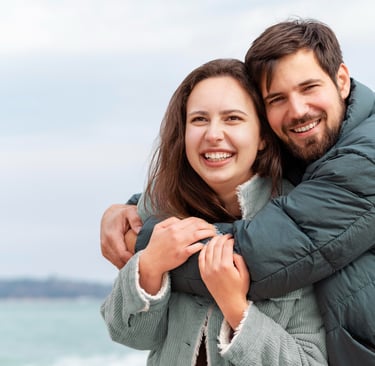 a man and woman hugging each other on a beach