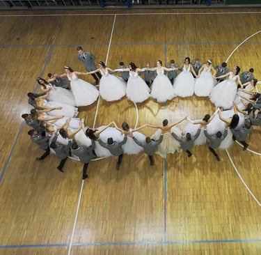 beltéri FPV drónos kép egy sportcsarnokban rendezett szalagavató bálról ahol ovális formában táncol