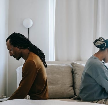 a man and woman sitting on a bed