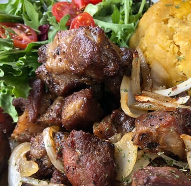 a plate of carne frita con mofongo and vegetables