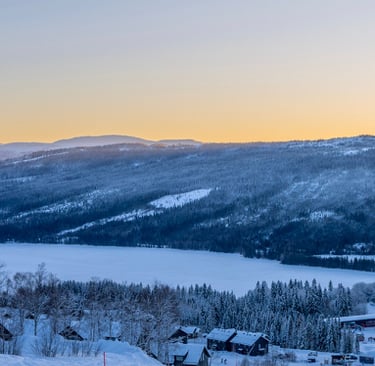 view of a snowy landscape on a piste during sunset