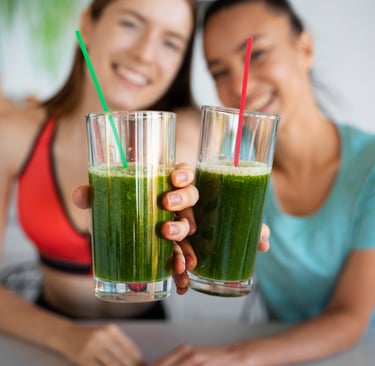 two women holding up two glasses of green juice