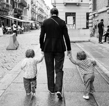 Mother takes her two children by the hand as the walk along the street in Milan, Italy