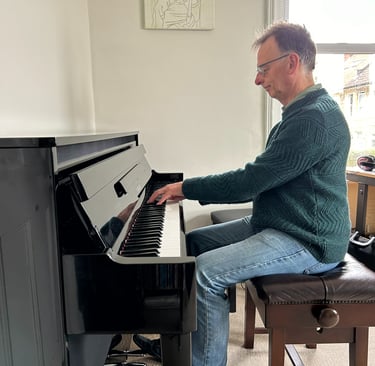 Photo of Steven playing an upright piano