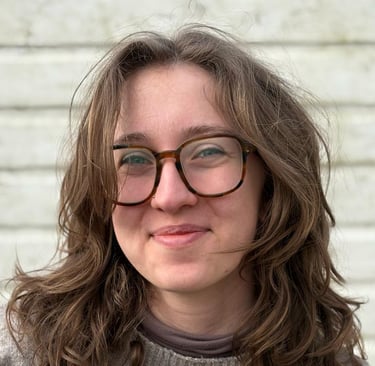junge Hebamme mit Brille und gewellten Haaren