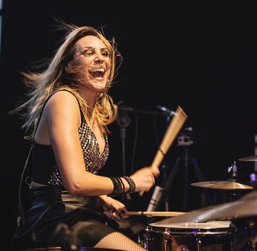 Singer Keka playing the drums while flipping her hair.