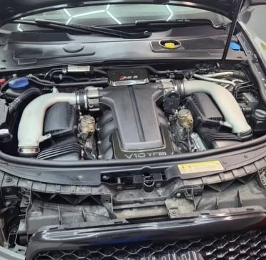 KFZ-Mechaniker arbeitet an einem Motor auf einem roten Montageständer in der Werkstatt.