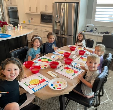Kids smiling while painting at a table